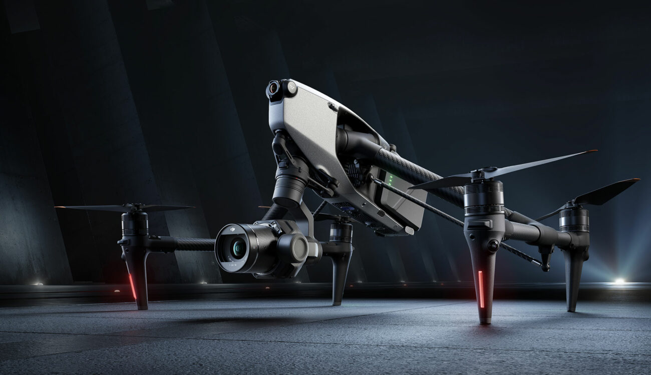 Профессиональный дрон DJI Inspire 3 с крупной камерой и стабилизатором, установленный на земле в тёмном индустриальном помещении, готовый к съёмке.